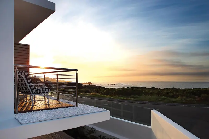 Terrasse avec mobilier d'extérieur donnant sur la mer au coucher du soleil.