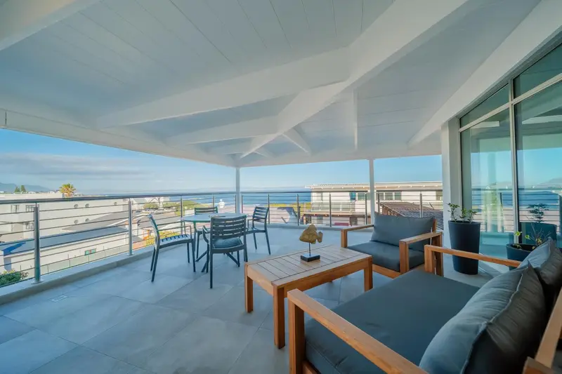 Terrasse aménagée avec salon et tables donnant sur la mer.