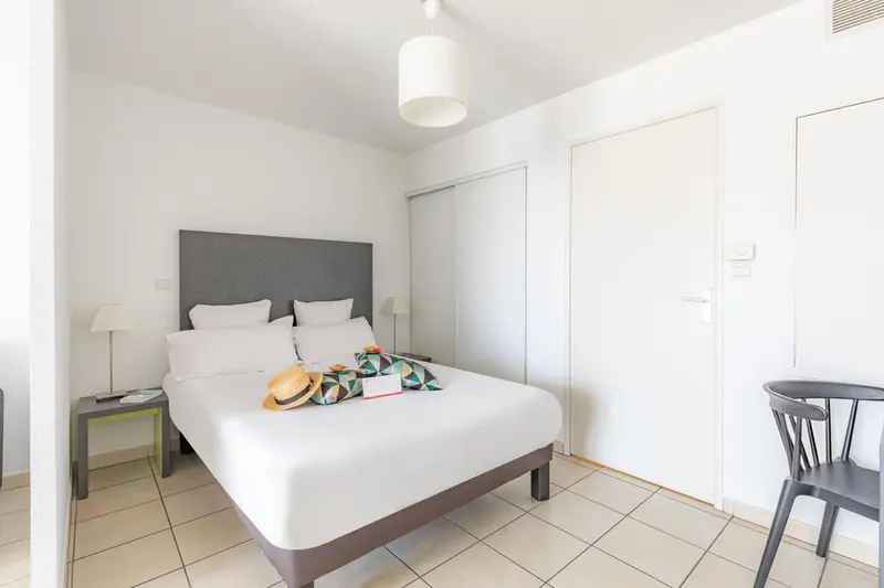 Une chambre lumineuse avec un grand lit et une table de chevet.