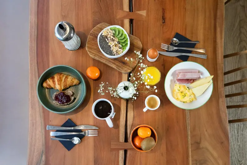 Table en bois servant un petit-déjeuner copieux avec des fruits, des céréales et des œufs.