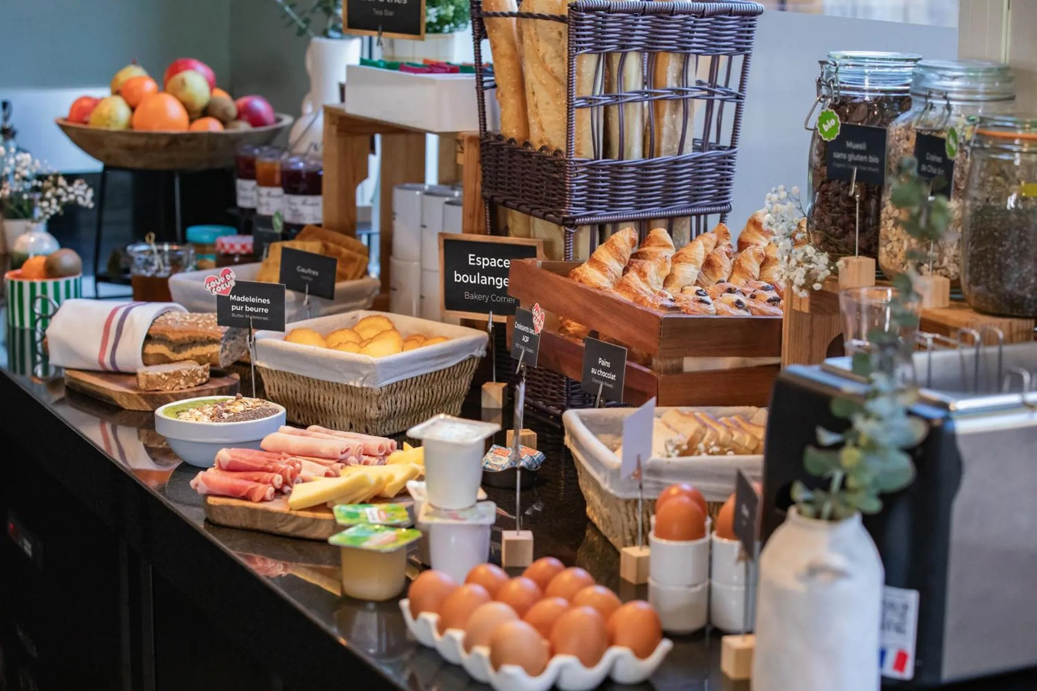 Un buffet propose une variété de viennoiseries, de fruits et de confitures.