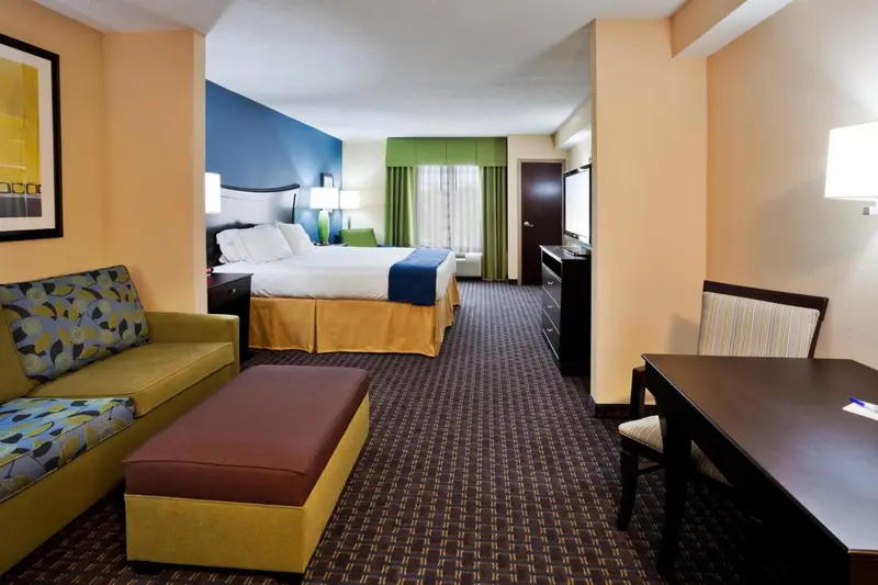Une chambre d'hôtel lumineuse avec un canapé, un bureau et un grand lit.
