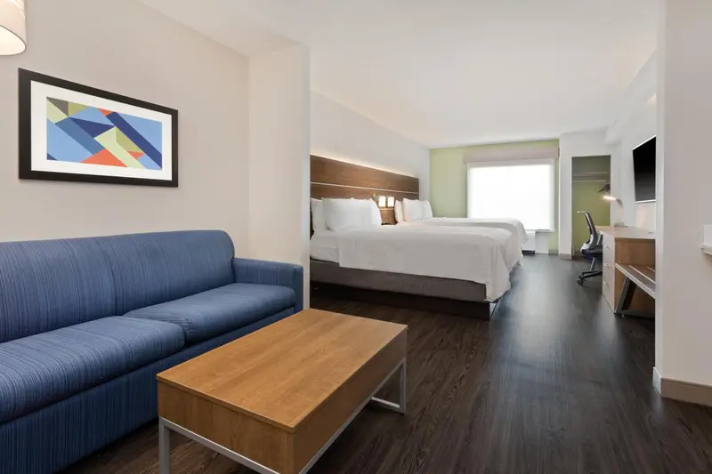 Une chambre lumineuse avec un canapé bleu et deux lits simples.