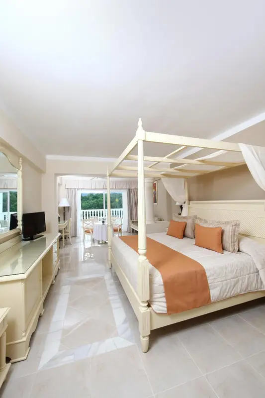Une chambre lumineuse avec un grand lit à baldaquin et vue sur l'extérieur.