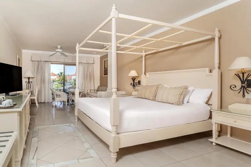 Une grande chambre lumineuse avec un lit à baldaquin et une décoration soignée.