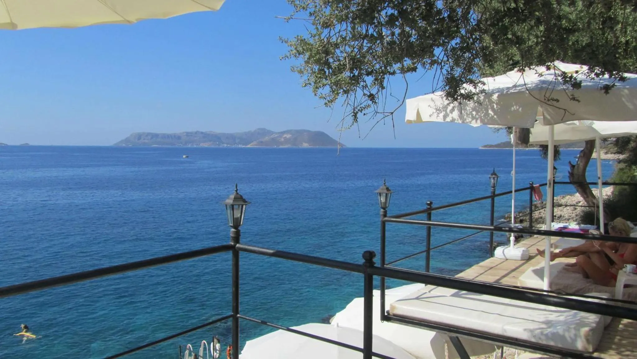 Vue sur la mer depuis une terrasse ensoleillée avec des transats.