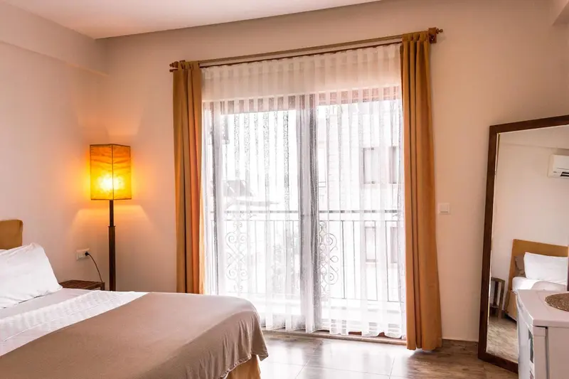 Une chambre lumineuse avec un grand lit et un accès à un balcon.
