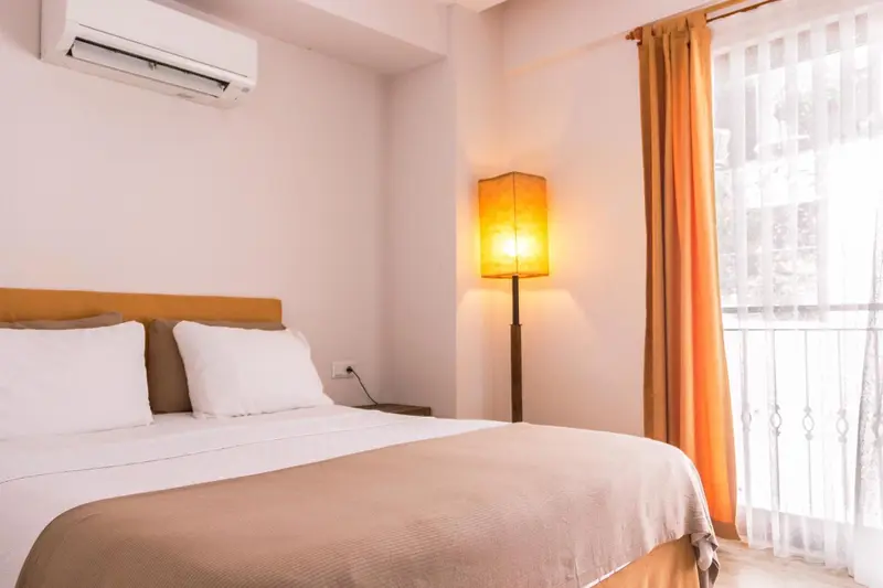 Une chambre lumineuse avec un grand lit et une lampe de chevet.