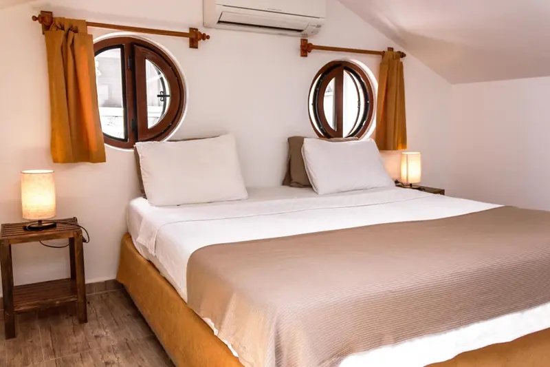 Une chambre lumineuse avec un lit double et des hublots.