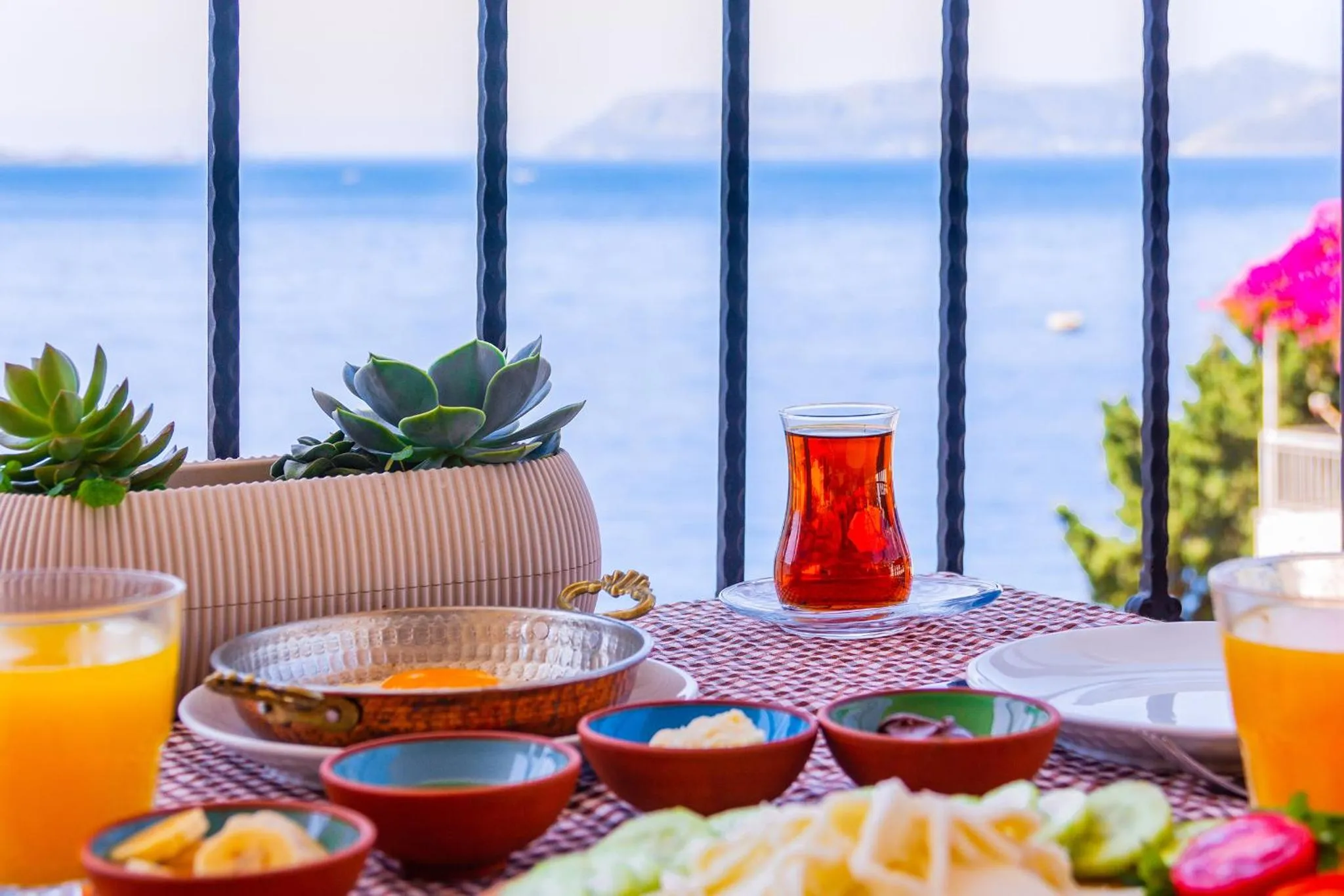Une table de petit-déjeuner est dressée sur une terrasse avec vue sur la mer.