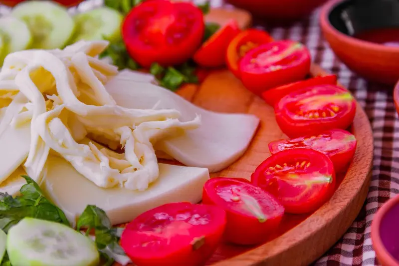 Assiette de crudités et de fromage frais présentées sur une planche en bois.