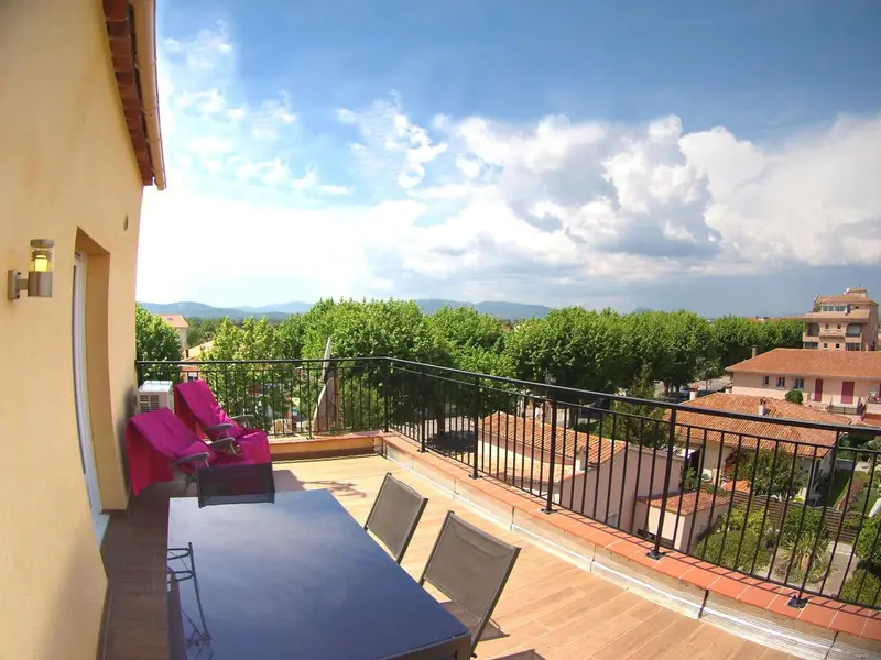 Terrasse avec mobilier de jardin et vue sur un paysage verdoyant.