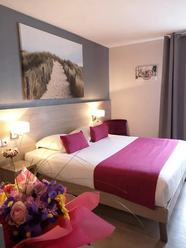 Une chambre d'hotel avec un grand lit recouvert d'une courtepointe rose et des oreillers.