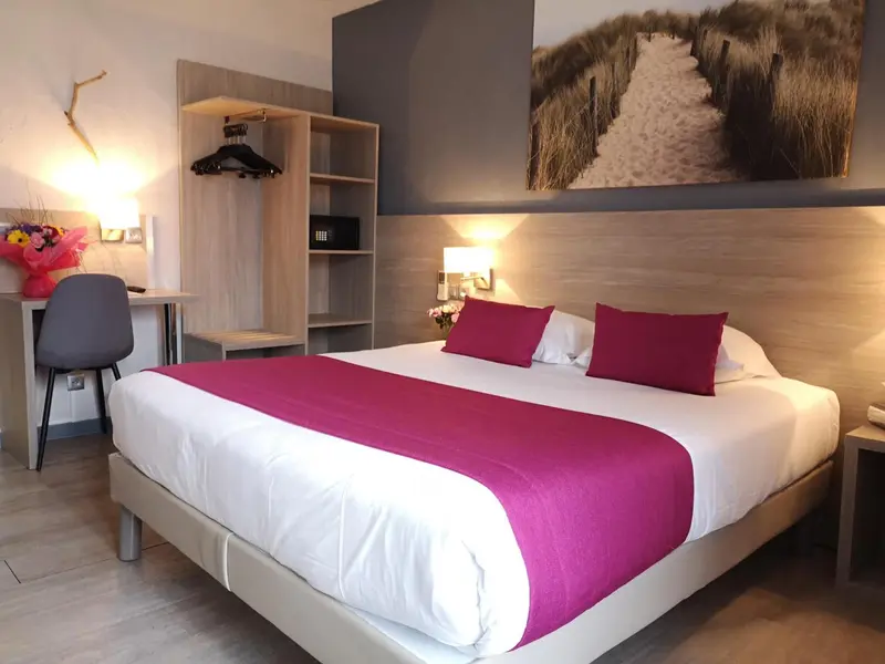 Une chambre d'hôtel moderne avec un lit recouvert d'une courtepointe rose et un bureau.
