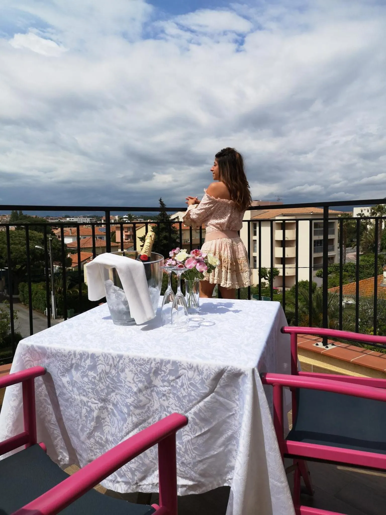 Une femme se tient sur une terrasse avec vue sur la ville.