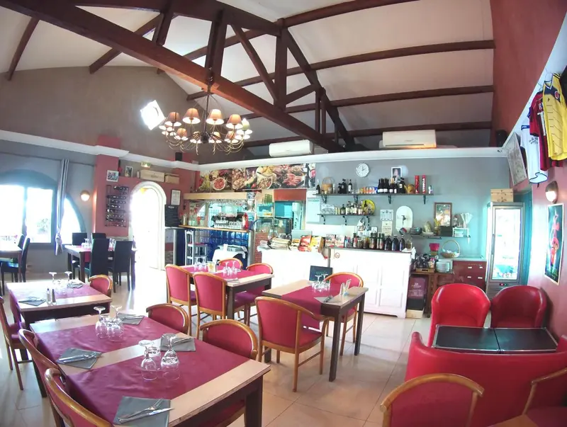 Une salle de restaurant lumineuse avec des tables dressées et un comptoir de bar.