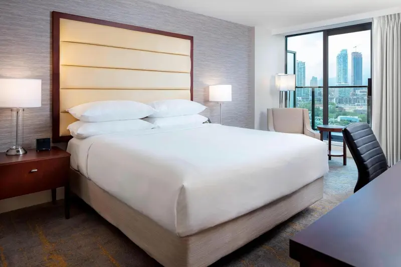 Une chambre d'hôtel lumineuse avec un grand lit et une vue sur la ville.