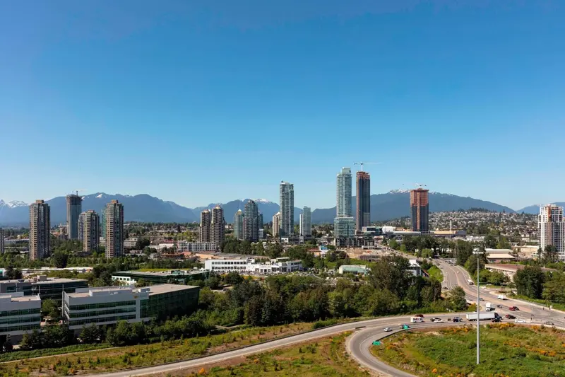 Vue panoramique sur une ville avec des gratte-ciel et des montagnes en arrière-plan.