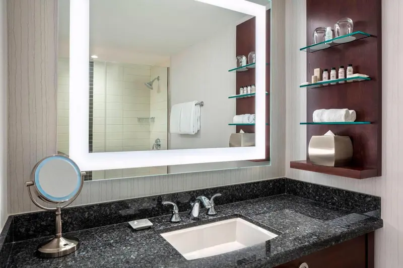 Une salle de bain moderne avec un grand miroir éclairé et des serviettes.