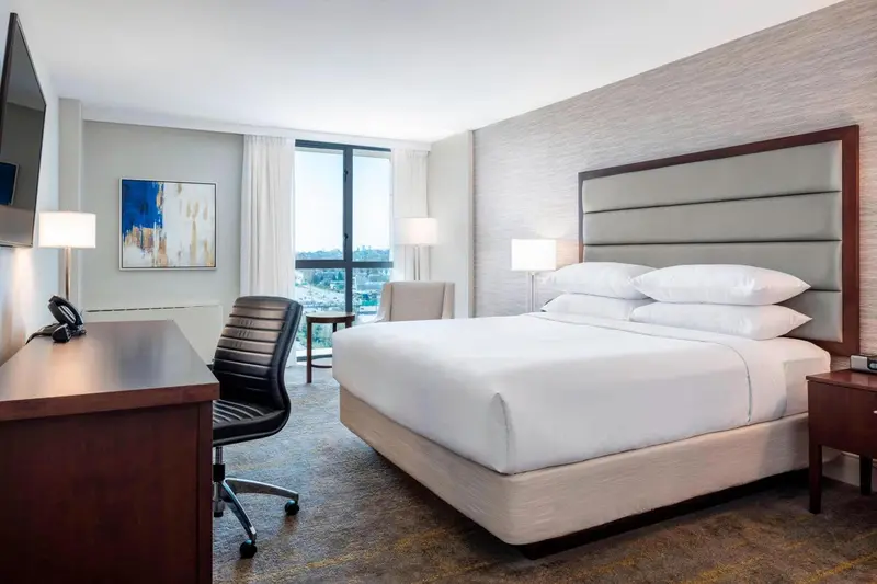 Une chambre lumineuse avec un grand lit et un bureau près de la fenêtre.