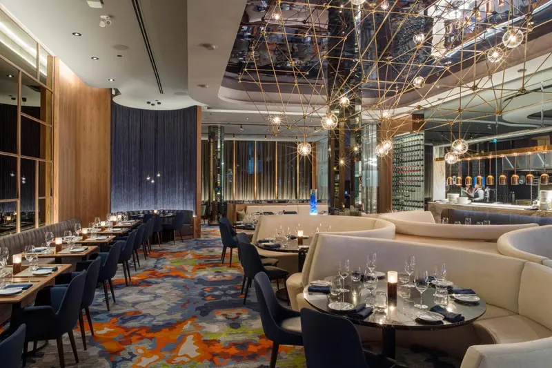 Une salle de restaurant élégante avec des tables dressées et un éclairage décoratif.