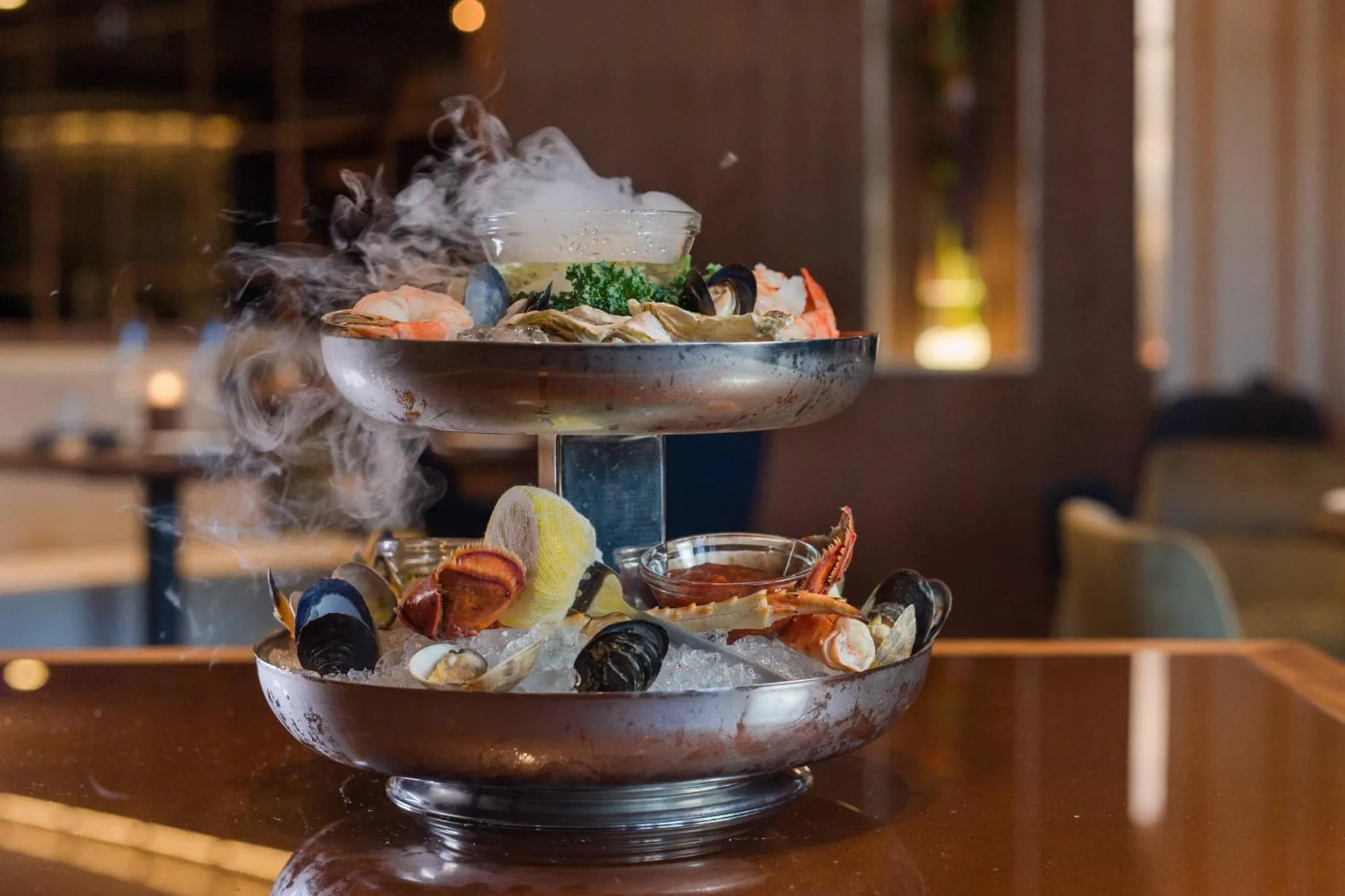 Présentation raffinée de fruits de mer et crustacés sur un plateau à deux niveaux.