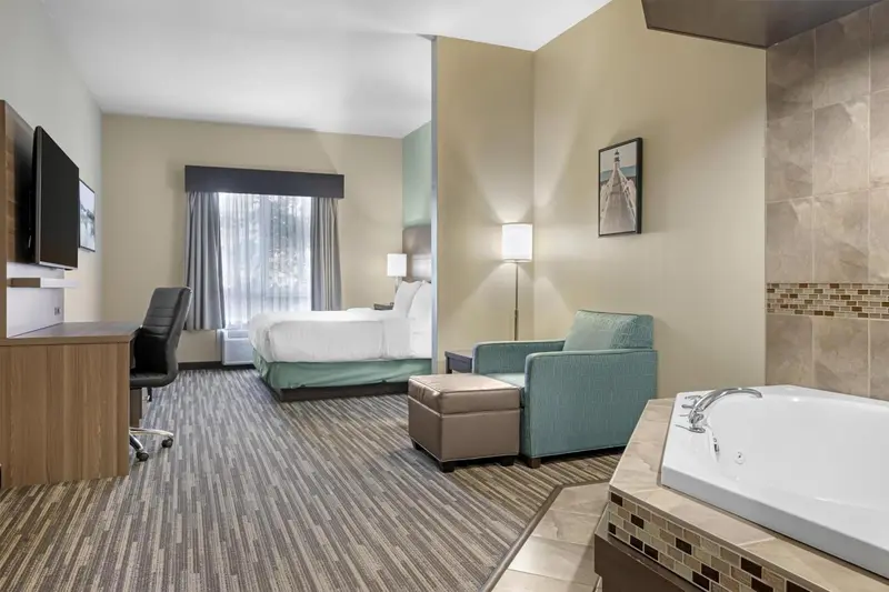 Une chambre lumineuse avec un lit, un coin salon et une baignoire à remous.