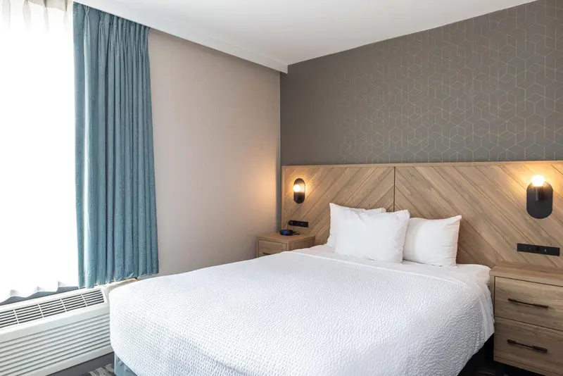 Une chambre d'hôtel lumineuse avec un lit double et des chevets.