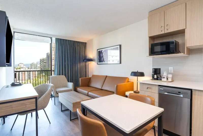 Espace de vie lumineux avec canapé, table basse et kitchenette.