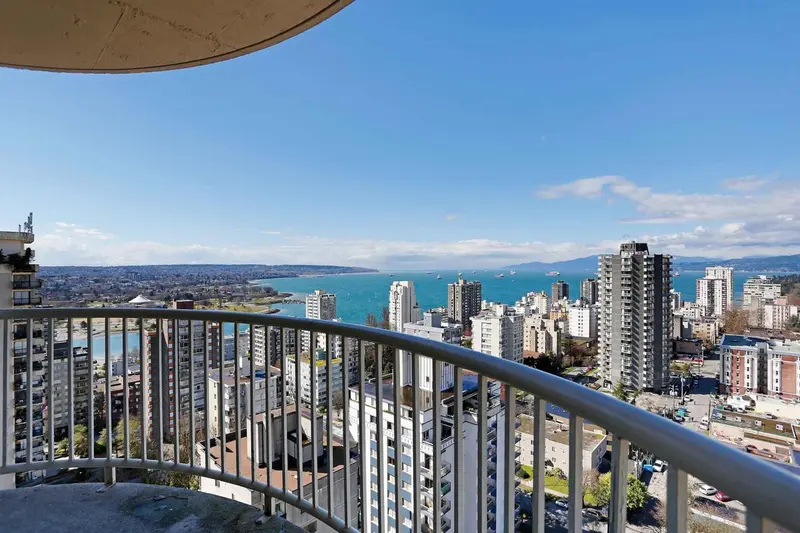 Vue panoramique sur la ville et la mer depuis un balcon.
