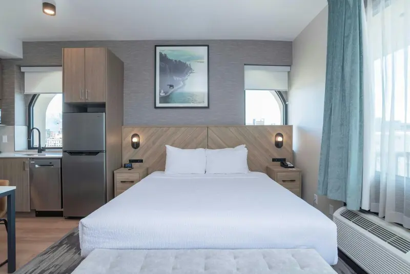 Une chambre lumineuse avec un grand lit et une kitchenette.