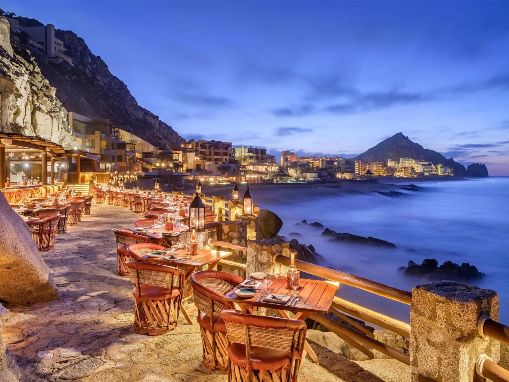 Terrasse de restaurant en bord de mer avec tables éclairées aux chandelles.