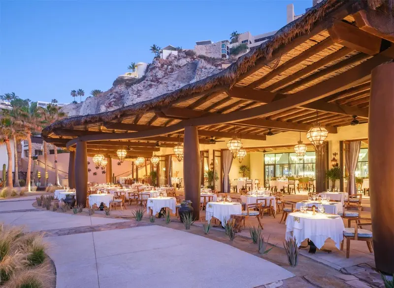 Terrasse de restaurant avec tables nappées et éclairage chaleureux.
