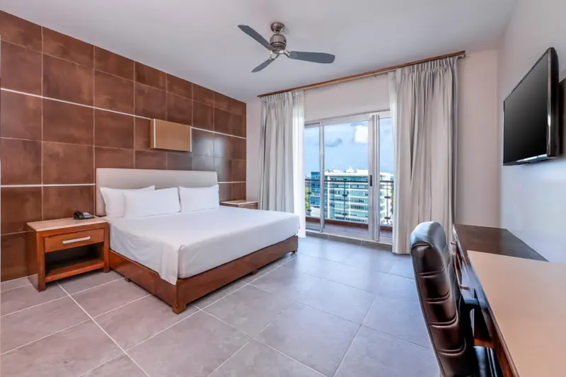 Une chambre d'hôtel lumineuse avec un grand lit et un accès à un balcon.