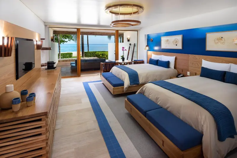 Chambre lumineuse avec deux lits et vue sur la mer.