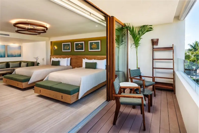 Une chambre lumineuse s'ouvre sur une terrasse avec des fauteuils en bois.