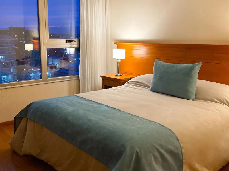 Une chambre lumineuse avec un grand lit et une vue sur la ville.