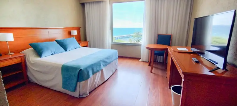 Une chambre lumineuse avec un grand lit et une vue sur la mer.