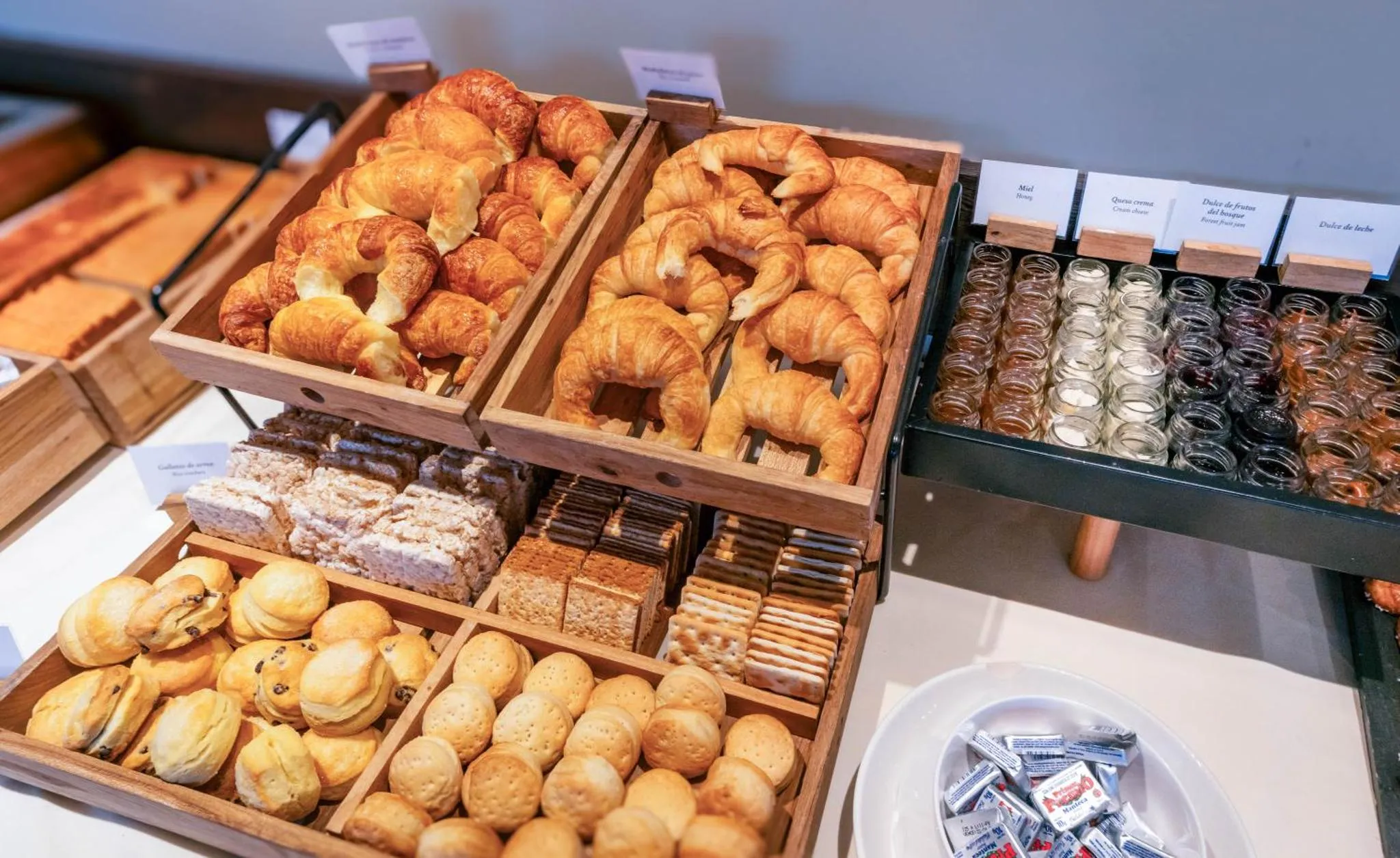 Présentation de viennoiseries et de confitures sur un buffet.