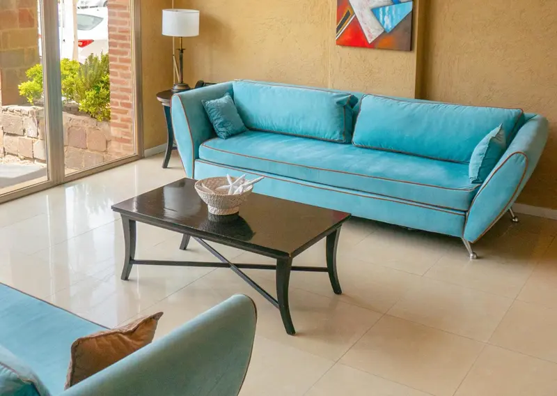 Un canapé bleu turquoise et une table basse en bois dans un intérieur lumineux.