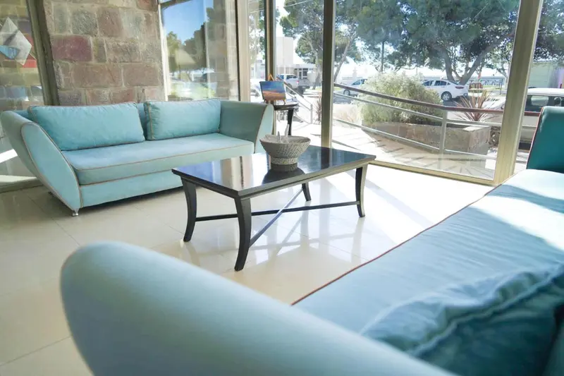 Un espace de détente intérieur avec canapés et table basse près d'une grande baie vitrée.