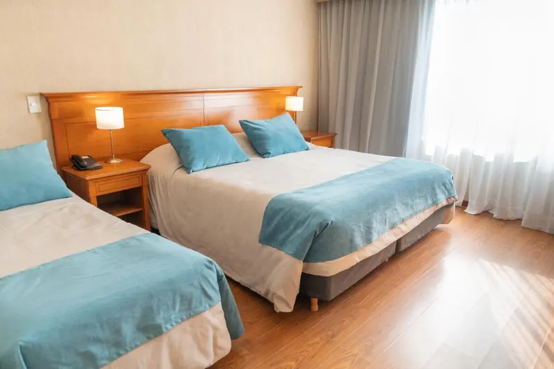 Une chambre lumineuse avec deux lits simples et un grand lit double.