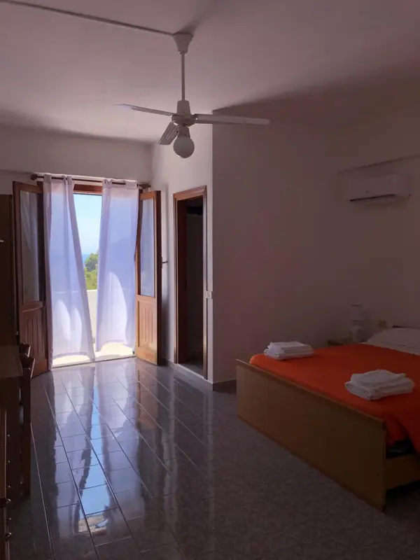 Chambre lumineuse avec un lit et un accès à une terrasse.