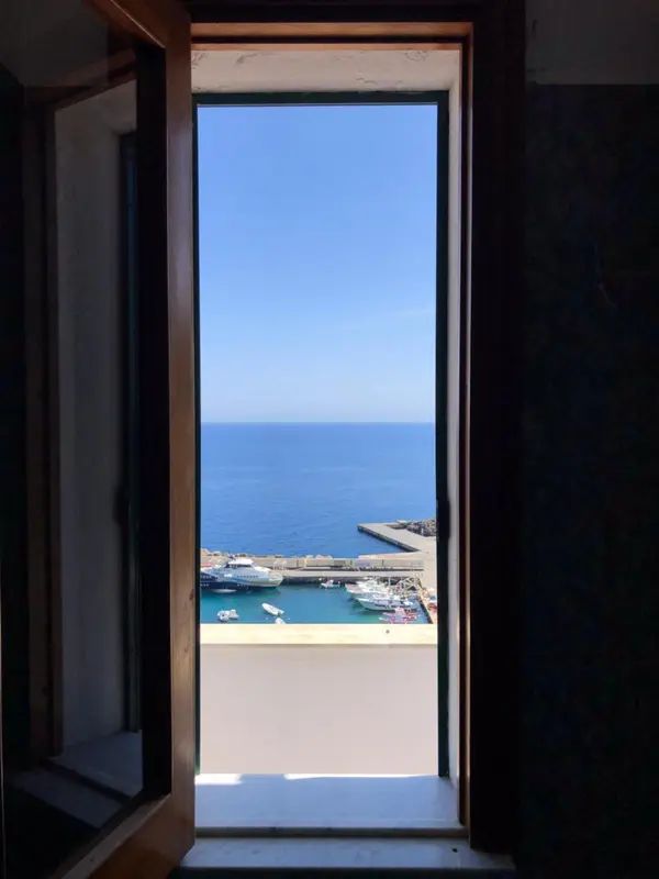 Vue sur la mer et un port depuis une ouverture.