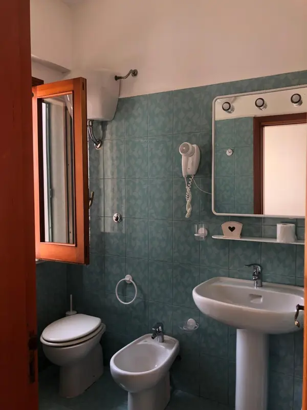 Une salle de bain claire avec carrelage vert et équipements sanitaires.