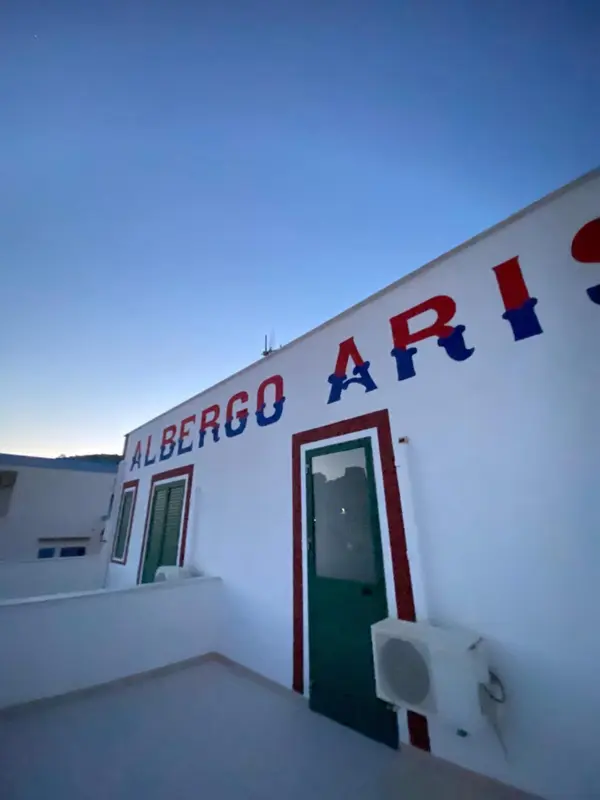 Façade blanche d'un bâtiment avec une inscription en lettres rouges et bleues.