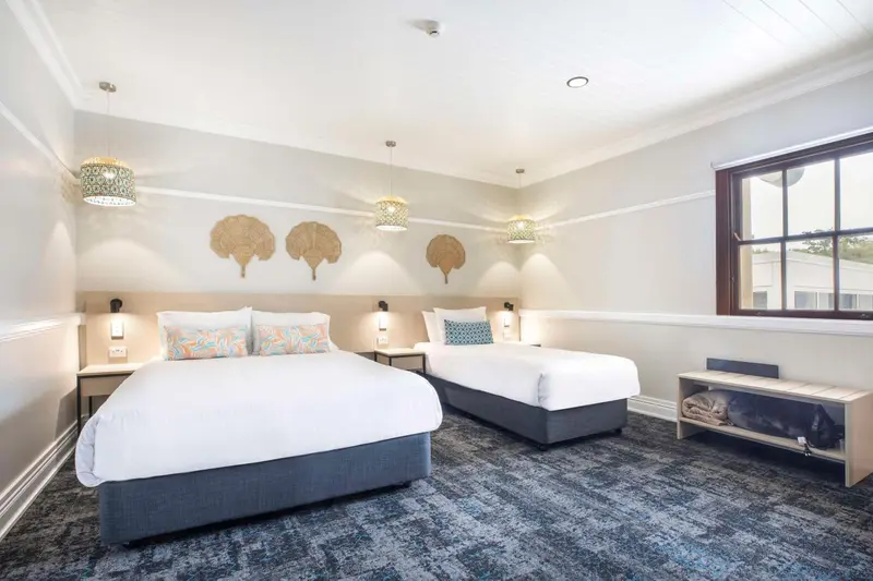 Une chambre lumineuse avec deux lits simples et une décoration murale.