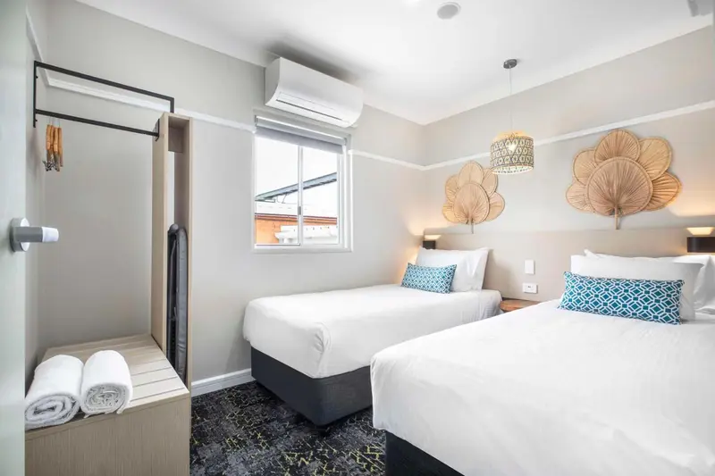 Une chambre lumineuse avec deux lits simples et une décoration murale.
