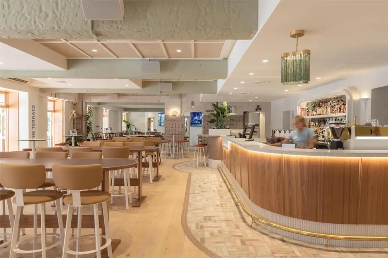 Un bar lumineux avec des tabourets et des tables en bois.