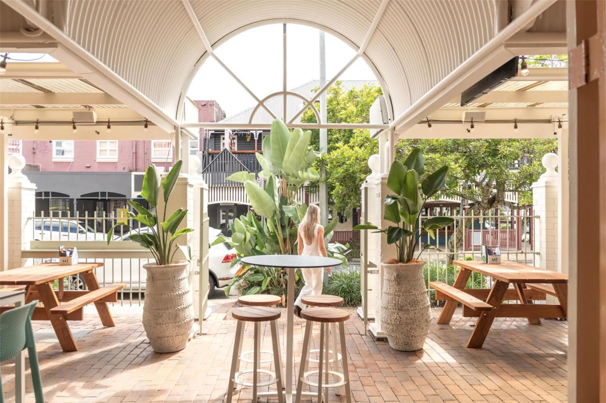 Terrasse ombragée avec tables et plantes tropicales.